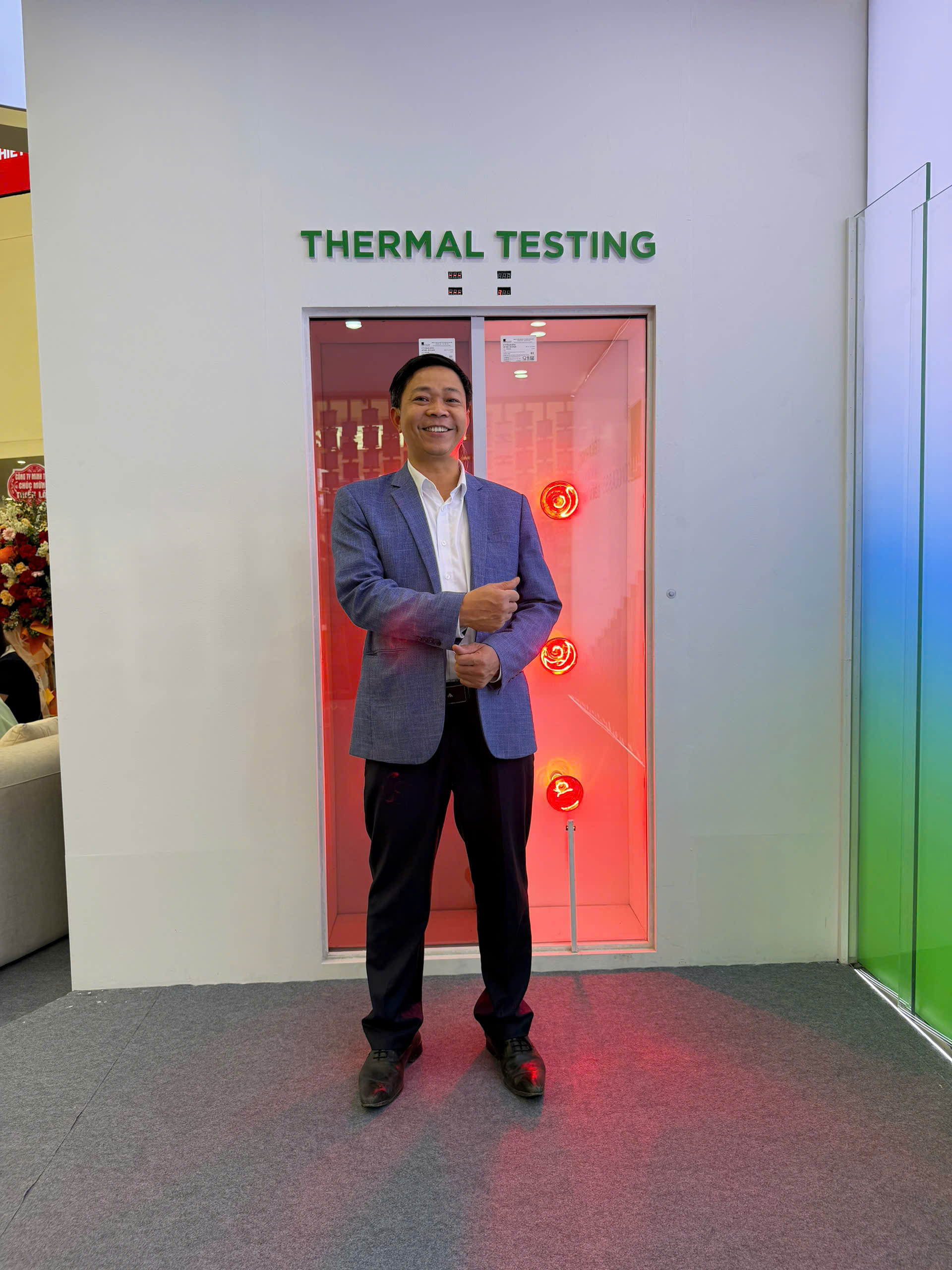 Người đàn ông đứng trước buồng thermal testing với hệ thống đèn nhiệt màu đỏ bên trong